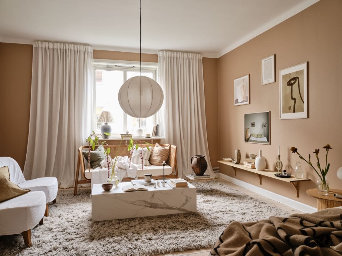 De lichte terracotta muren in deze mooie woonkamer zorgt voor een zachte, elegante look. | Fotografie: Janne Olander