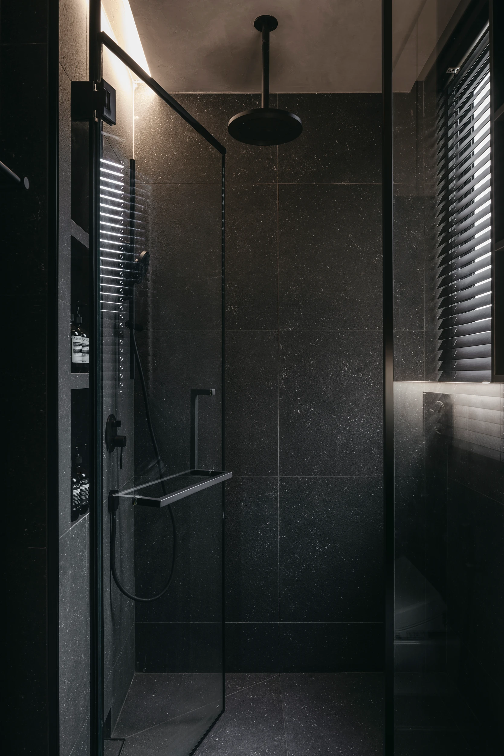 Deze luxe moderne badkamer, is ontworpen door Studio Metanoia, die gekozen heeft voor zwarte tegels op de vloer als aan de wanden.