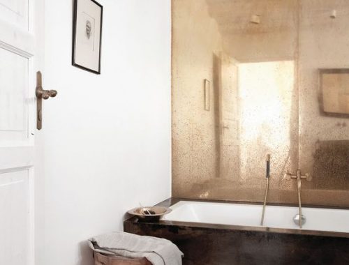 In deze badkamer zijn de meeste wanden strak en wit. Maar de muur bij het bad is bekleed met een hele bijzondere gouden plaat. Super nice!