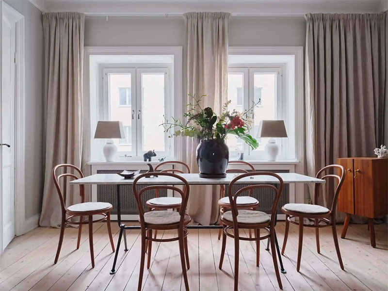 De marmeren eettafel vormt de perfecte balans in deze eethoek met houten vloer, houten eetkamerstoelen en een houten dressoir.