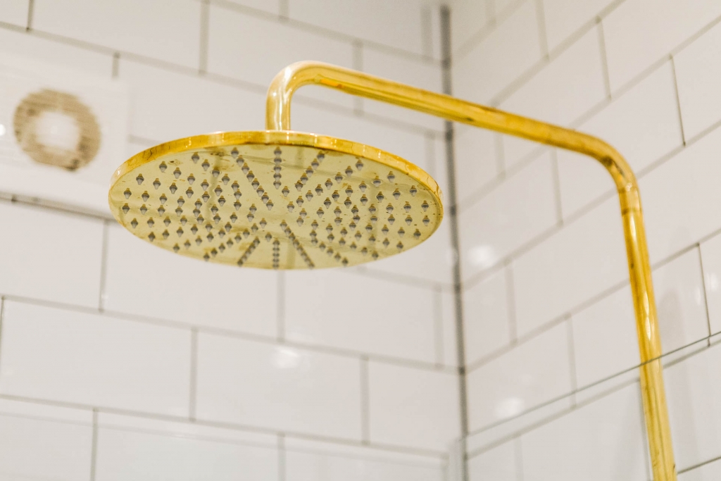 Deze kleine badkamer is afgewerkt met mooie gouden details