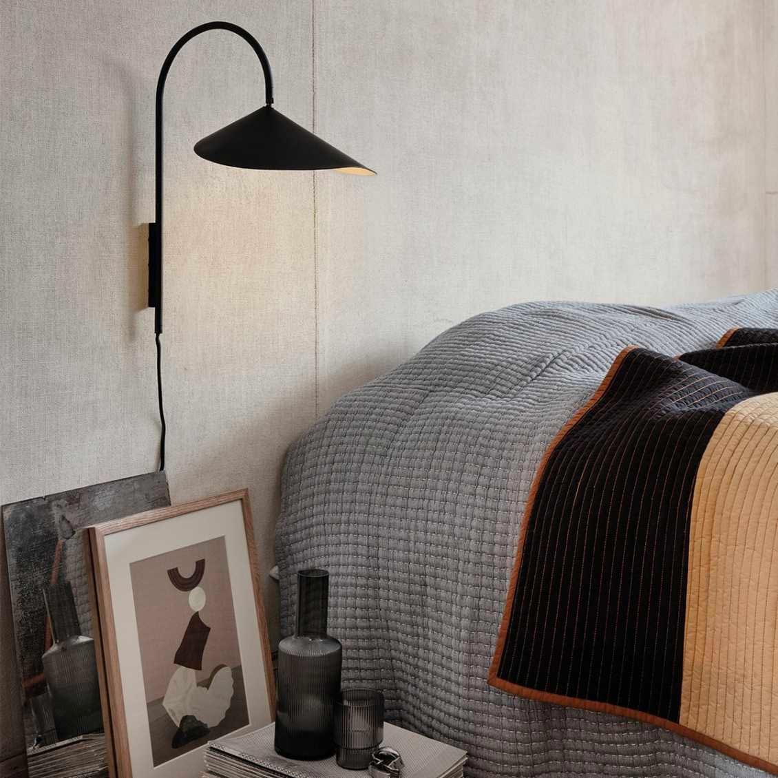 Hier hangt de Ferm Living Arum wandlamp subtiel boven het nachtkastje naast het bed.