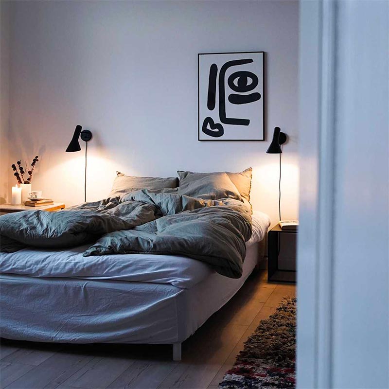 In deze stijlvolle slaapkamer is aan weerszijden de Louis Poulsen wandlamp opgehangen.