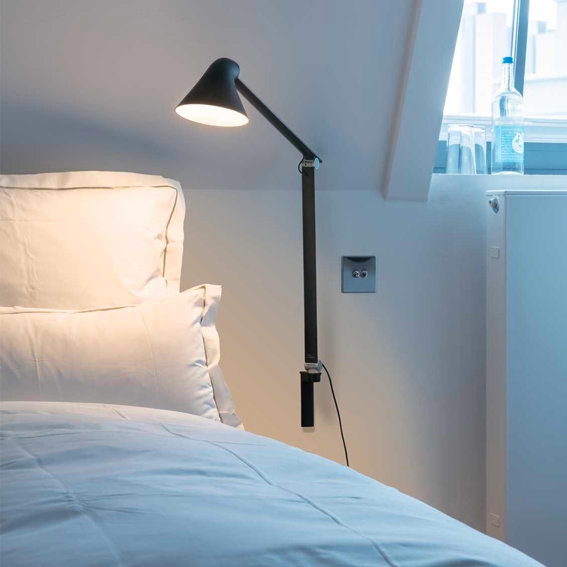 Minimalistische stijlvolle zwarte lamp in een witte slaapkamer.