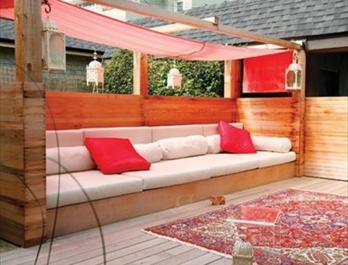 Een heerlijke op maat gemaakte loungebank met comfortabele kussens en rode schaduwdoek.