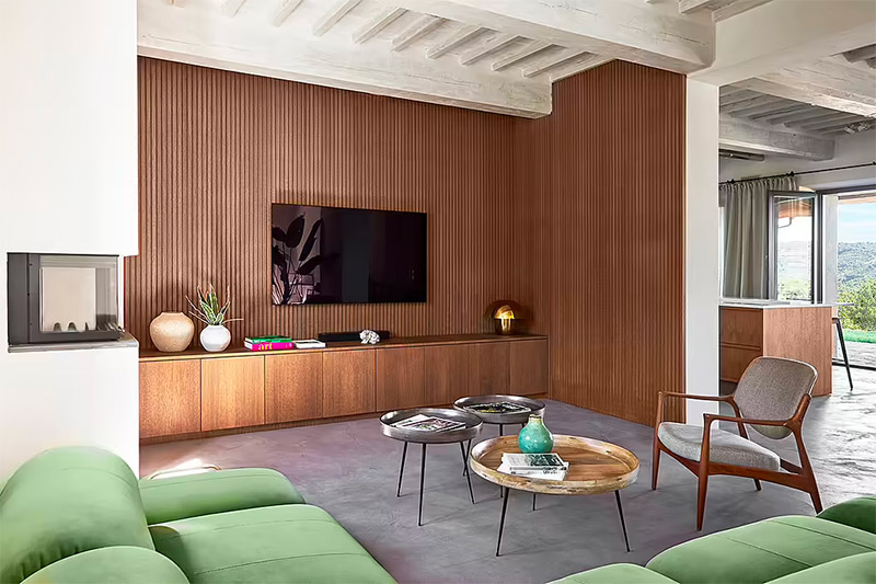 Special Umbria heeft deze prachtige luxe woonkamer ontworpen, met onder andere een houten wandbekleding, met daaraan een op maat gemaakte TV meubel, en een geweldige groene fluwelen bank.