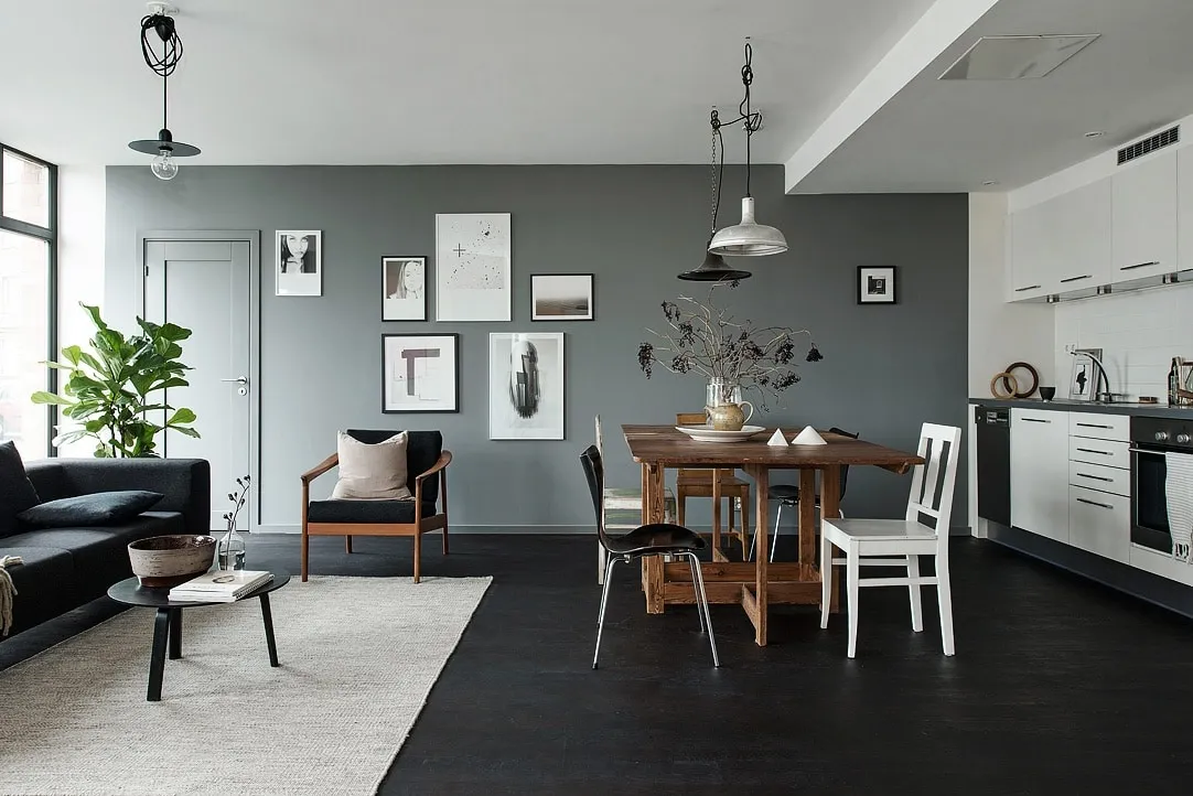 In dit moderne appartement, met een witte en grijze muren, zorgt de zwarte houten vloer voor sfeer en warmte.