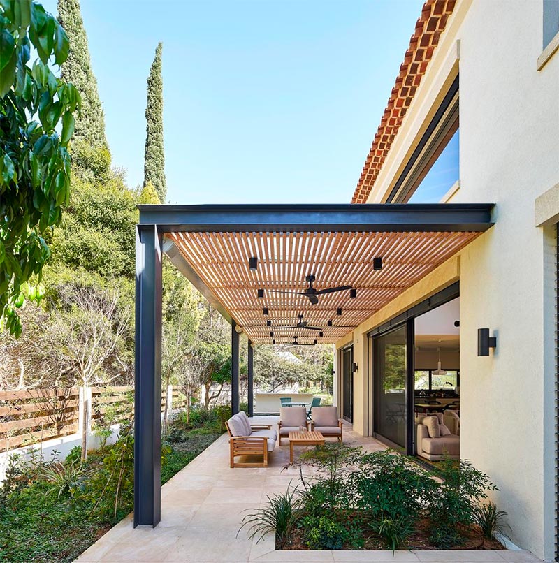 Daniel Arev Architecture heeft voor dit moderne terras gekozen voor een strakke tuinoverkapping met een stalen frame, gecombineerd met houten latten.