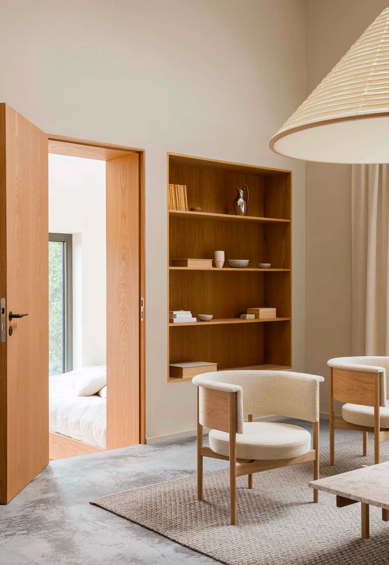Dit prachtige interieur is ontworpen door Norm Architects, gekenmerkt door mooie natuurlijke materialen. In de woonkamer is een grote nis gecreëerd, waar een grote houten boekenkast is gemaakt.