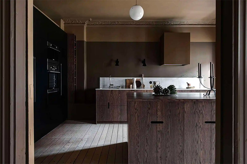 Een prachtige moody keuken waar een donkere taupe kleur gecombineerd is met hout.