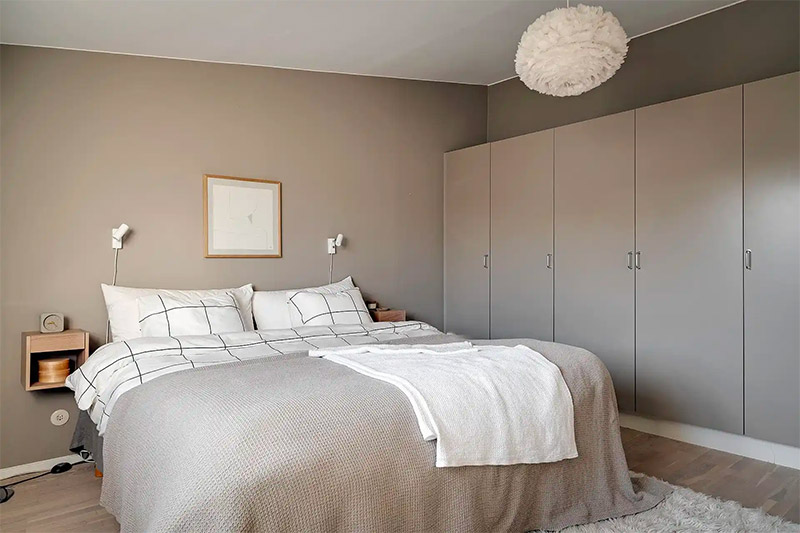 Naast de taupe muren in deze slaapkamer, is ook de grote kledingkast en de bedsprei in een mooie taupe kleur.