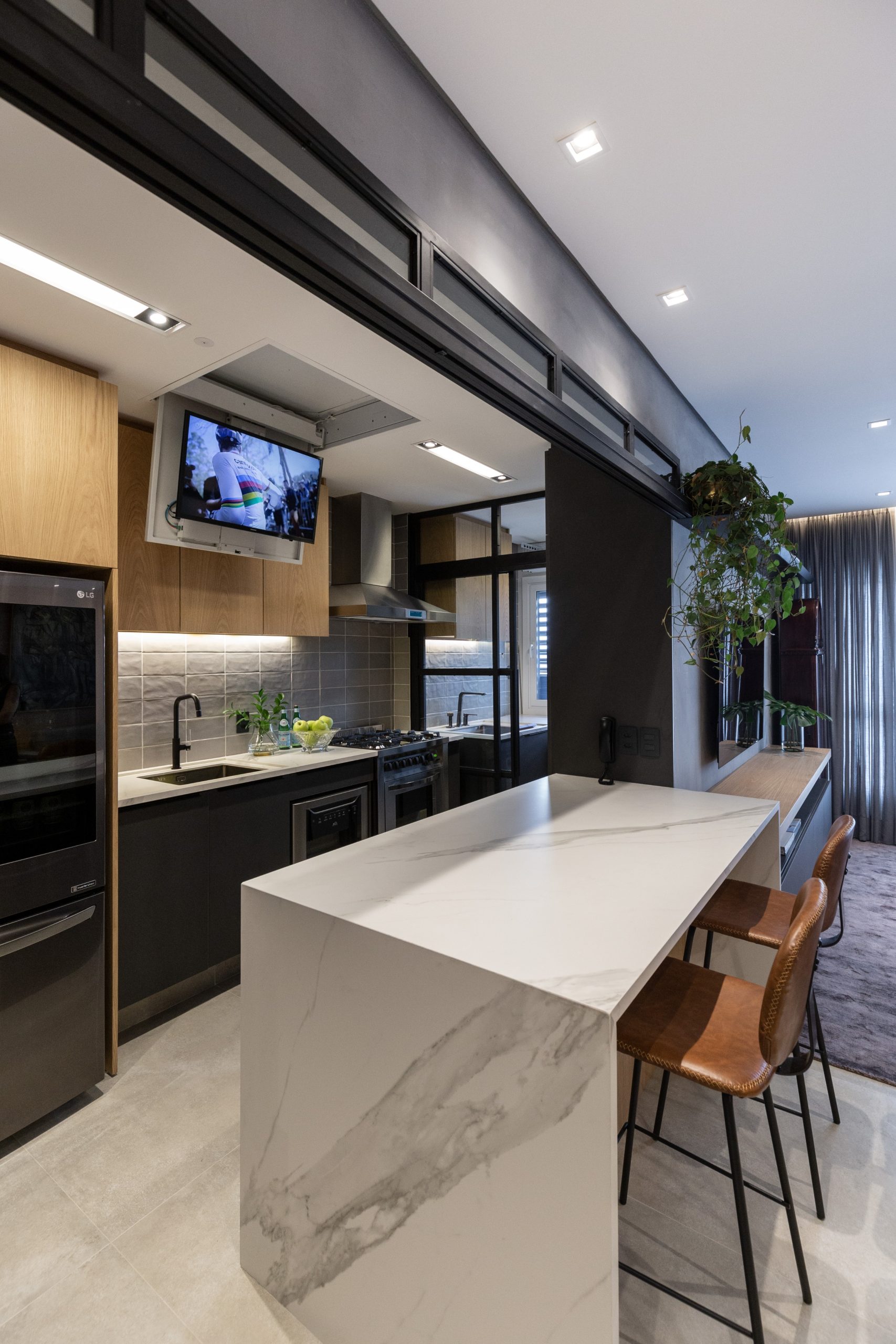 Een moderne keuken, ontworpen door 6mm Arquitetura, waar de TV aan het plafond is gemonteerd, een eenvoudig ingeklapt en verborgen kan worden.
