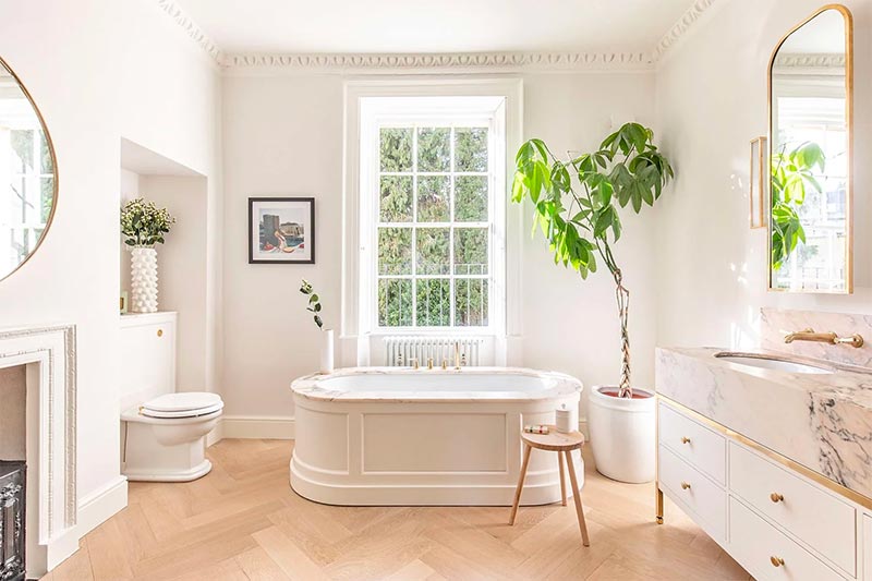 In deze badkamer met een klassiek vrijstaand bad, is er gekozen voor een prachtige visgraat houten vloer - Ontwerp van Laurabutlermadden.com