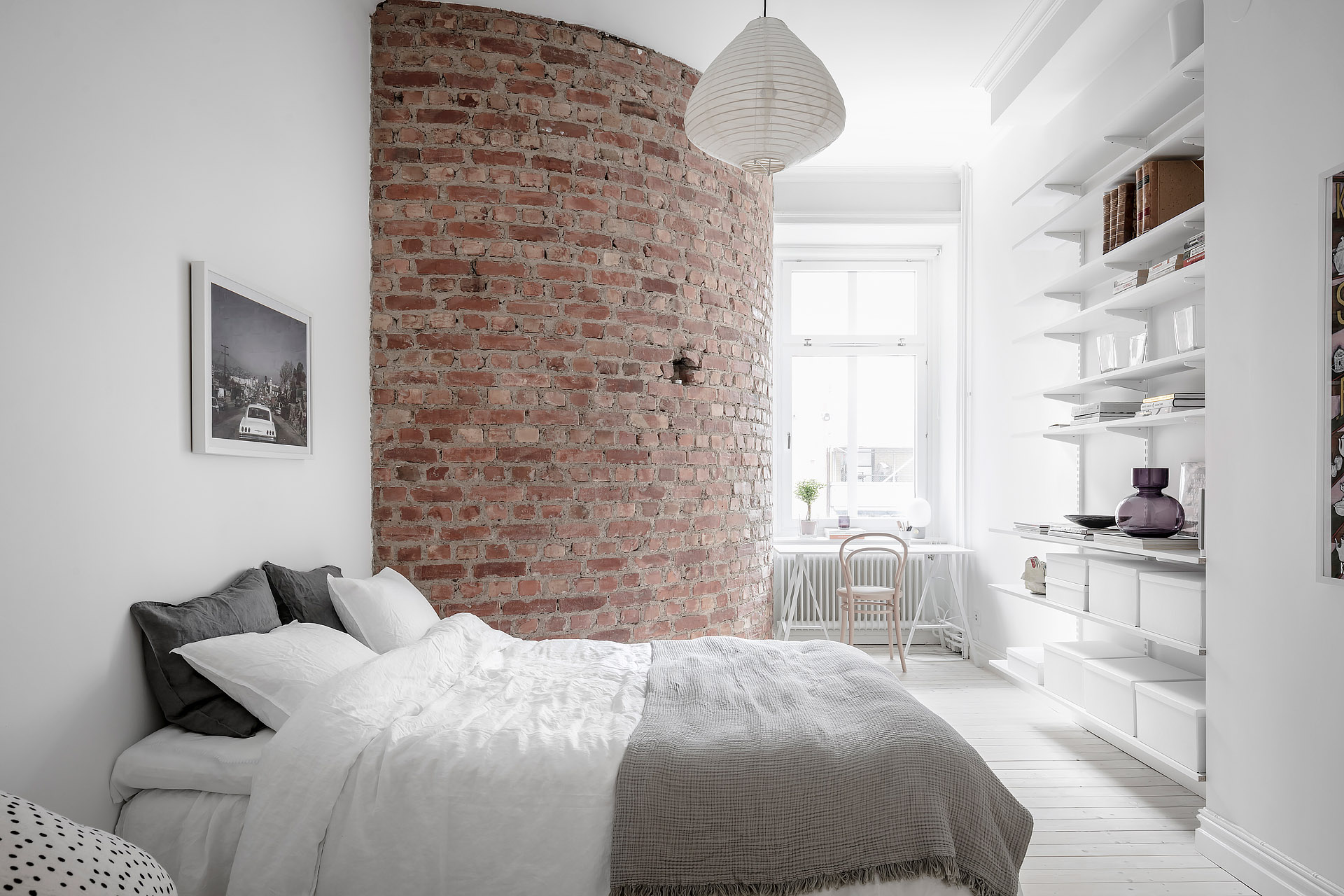Deze witte slaapkamer is voorzien van een super charmante ronde bakstenen muur