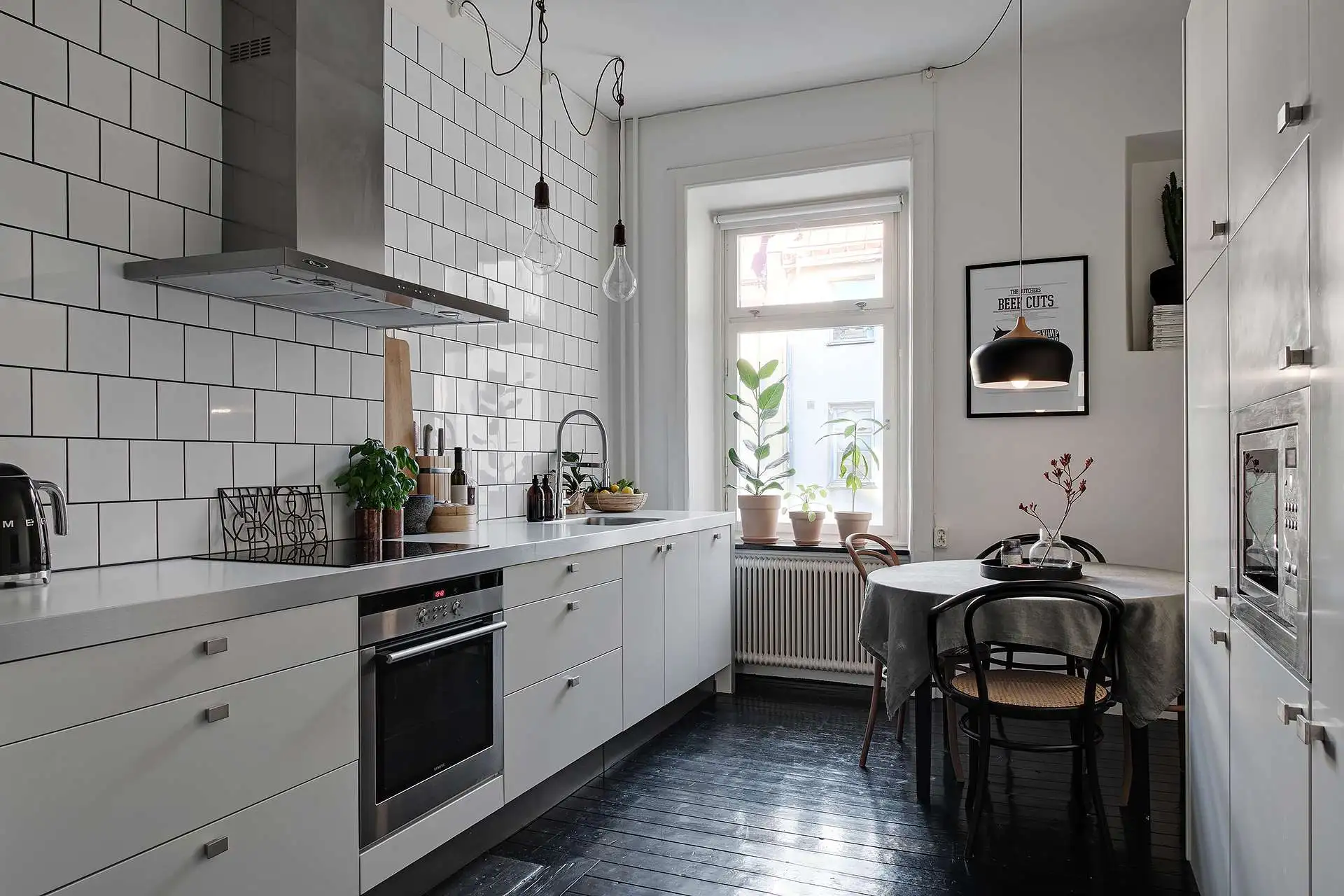 In deze mooie keuken is de houten vloer zwart geverfd, gecombineerd met een moderne witte keuken en een met witte tegels betegelde keuken achterwand.